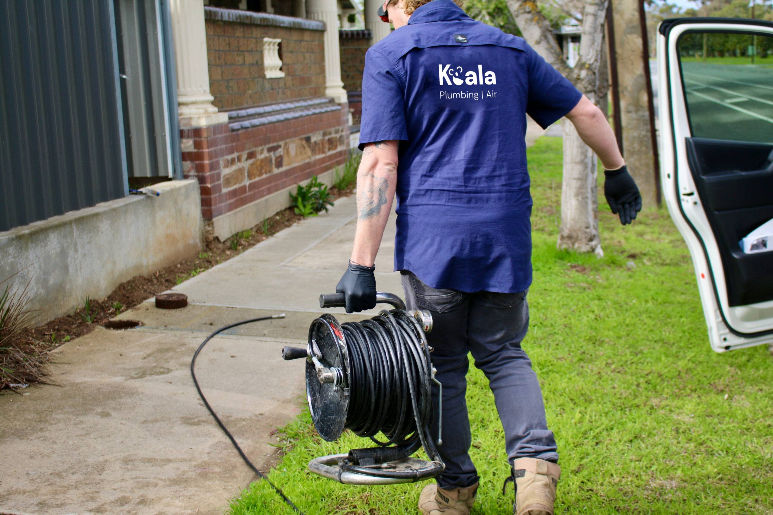 Koala Plumbing plumber carrying equipment
